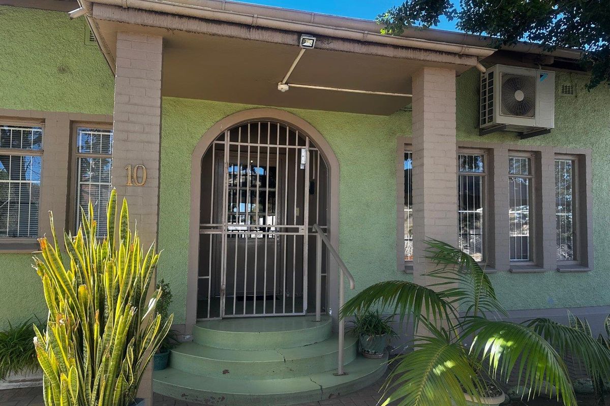 Front entrance of a mixed-use property featuring a covered porch, security gate, and exterior air conditioning unit.