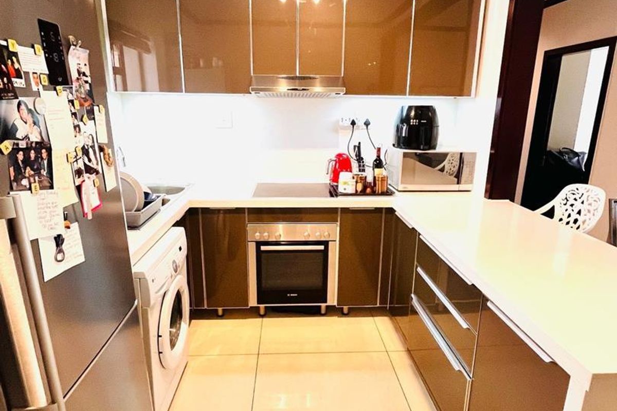 Modern kitchen featuring high-gloss cabinetry, stone countertops, integrated oven and hob, and a functional breakfast bar layout.