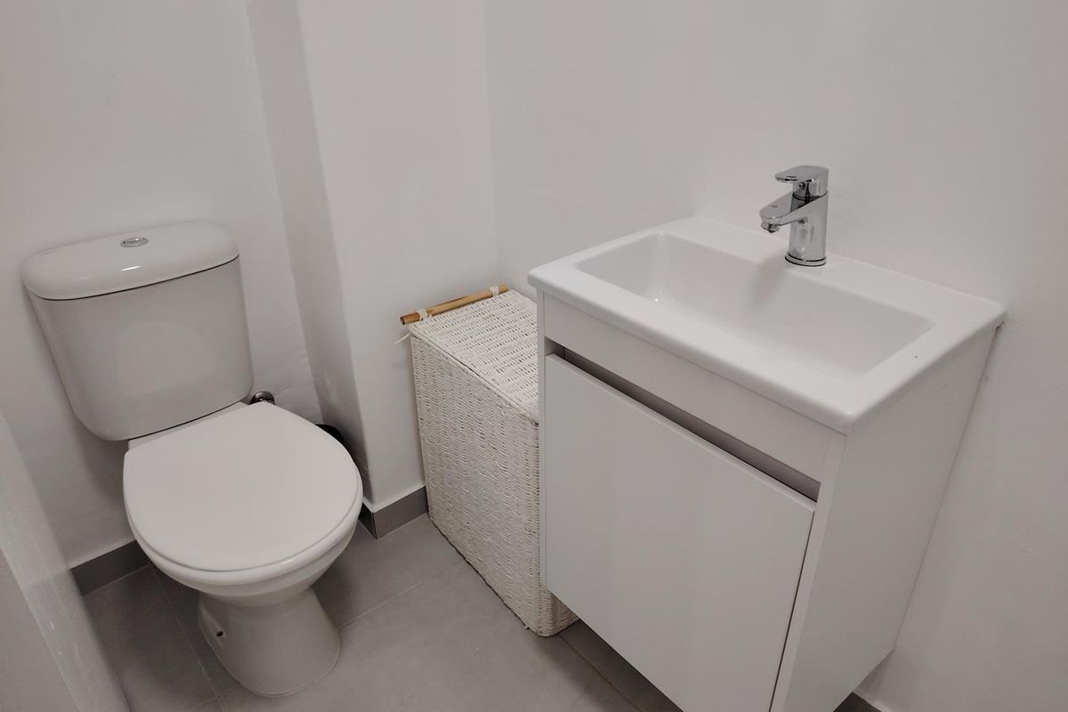 A clean and modern bathroom featuring a white vanity cabinet with a basin, chrome faucet, and a standard toilet.