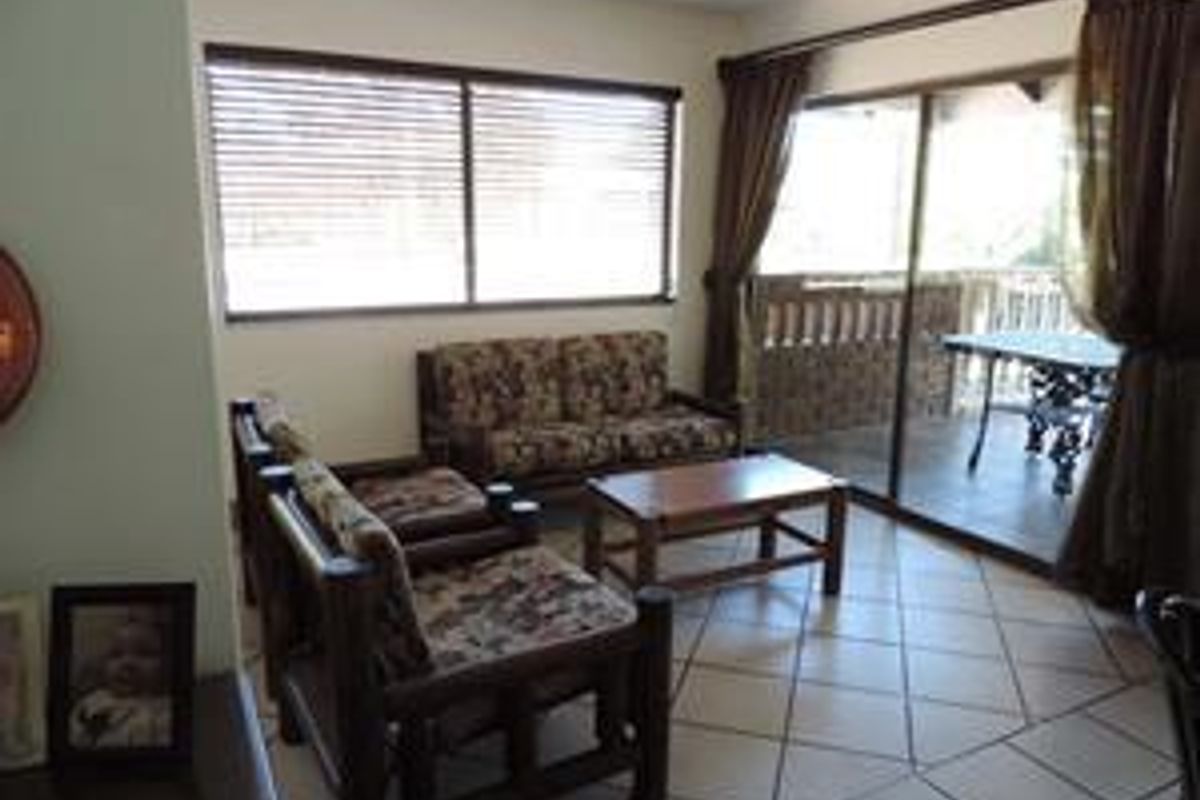 A living room featuring tiled flooring and large sliding glass doors that provide access to an outdoor patio area.