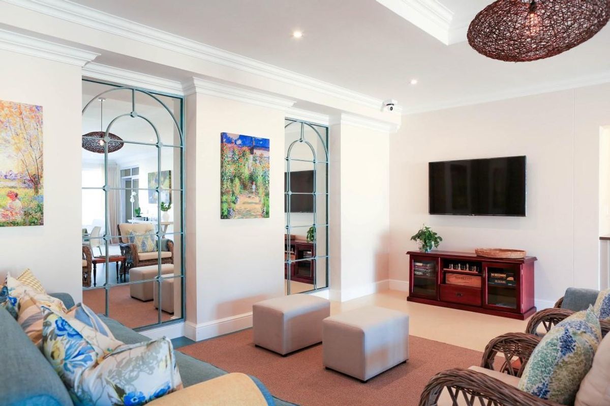 A well-maintained living room featuring elegant crown molding, recessed lighting, and distinctive arched decorative wall mirrors.