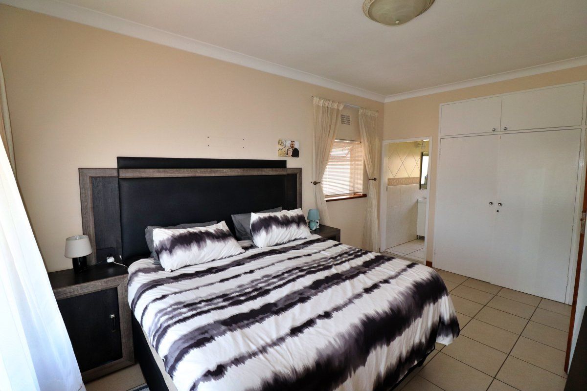 A bedroom featuring tiled flooring, built-in cupboards, and direct access to an en-suite bathroom.