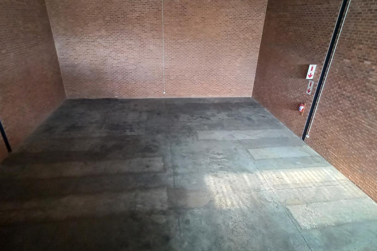 Spacious industrial utility area featuring exposed brick walls and durable concrete flooring, equipped with essential fire safety equipment.
