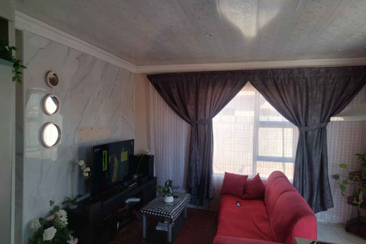 A cozy living room featuring a marble-effect feature wall with integrated circular lighting and large windows with curtains.