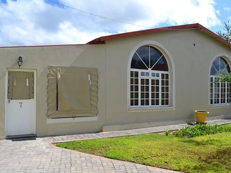 Front exterior view of a guest house unit featuring arched windows, a paved walkway, and a neutral-toned facade.