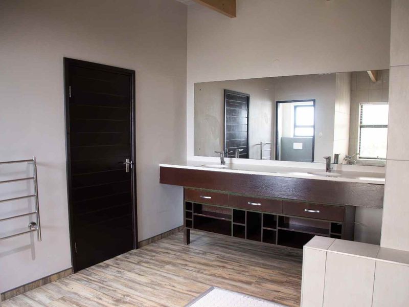 Modern bathroom featuring a double vanity with built-in cabinetry, a large wall mirror, and a heated towel rail.