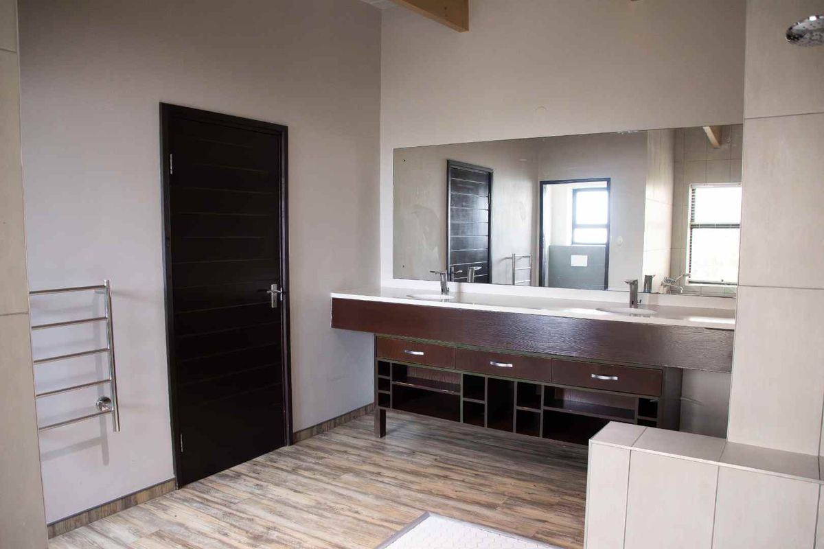Modern bathroom featuring a double vanity with built-in cabinetry, a large wall mirror, and a heated towel rail.