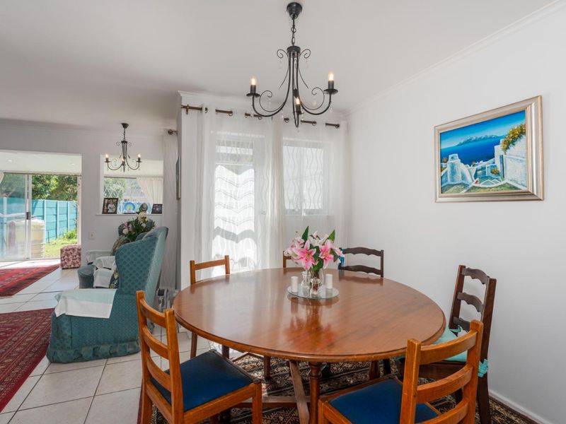 Open-plan dining and living area featuring tiled flooring, a classic chandelier, and sliding glass doors providing access to the outdoor space.
