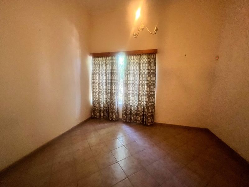 An empty bedroom featuring tiled flooring and a central ceiling light fixture, presenting a blank canvas for potential renovation or staging.