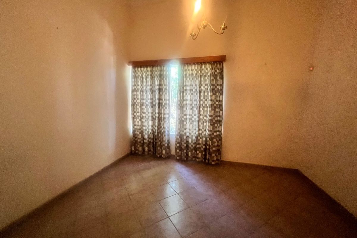 An empty bedroom featuring tiled flooring and a central ceiling light fixture, presenting a blank canvas for potential renovation or staging.