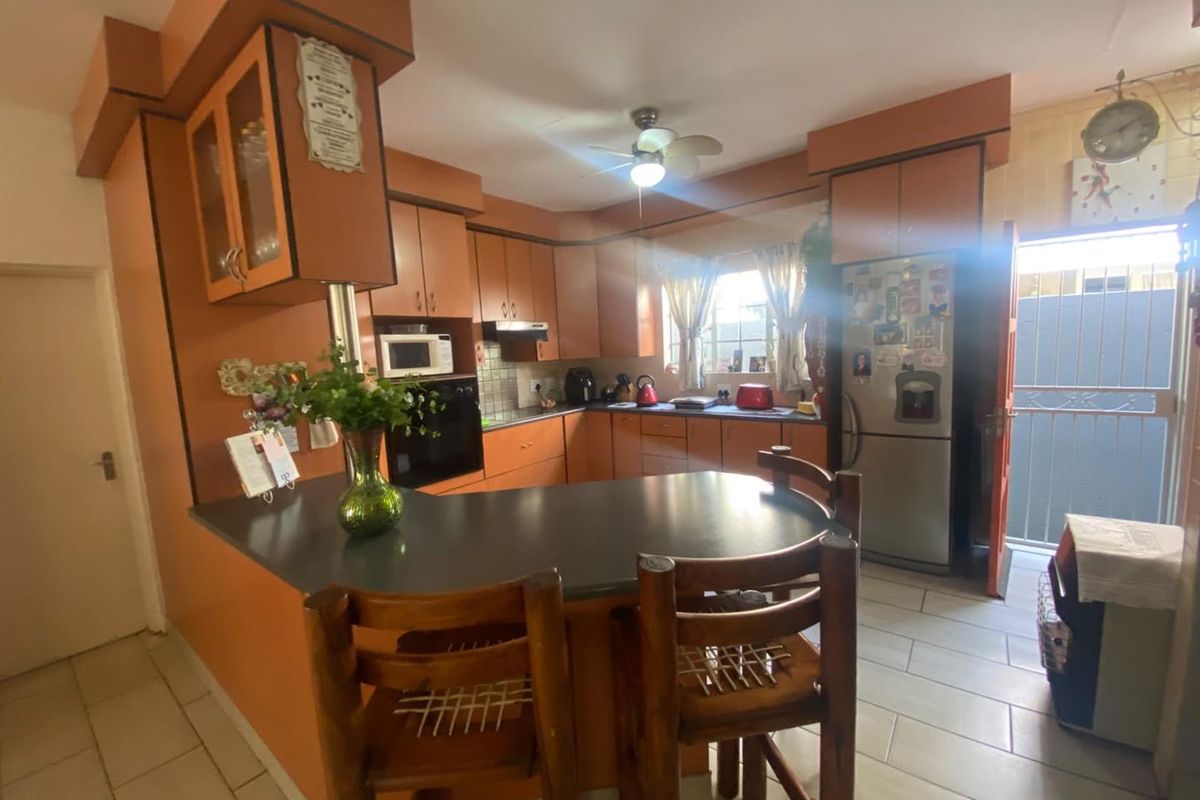 A functional kitchen featuring built-in cabinetry, a breakfast bar, and tiled flooring, with direct access to an outdoor area.