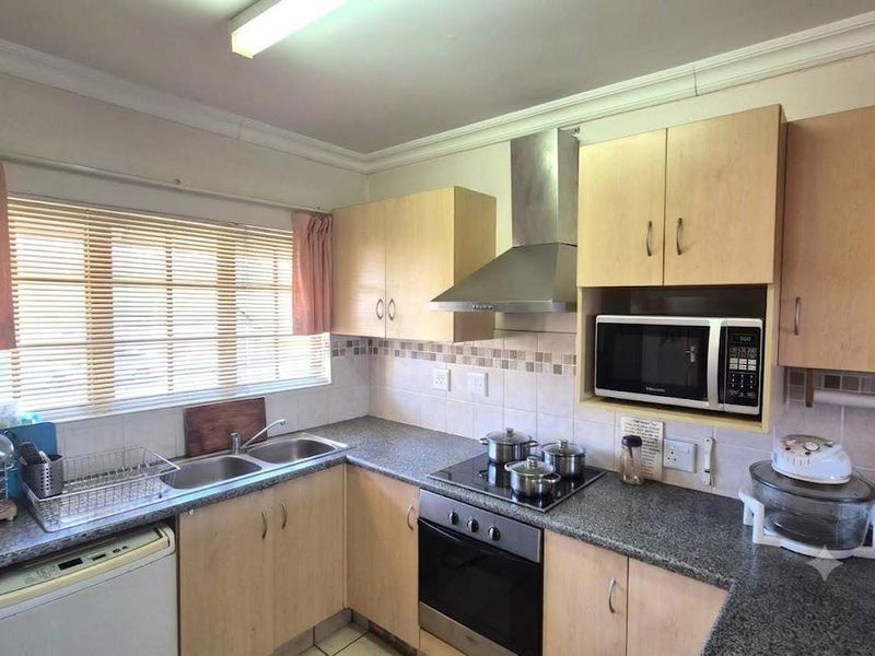 Functional kitchen featuring laminate cabinetry, granite countertops, stainless steel extractor fan, built-in oven, and a double bowl sink with tiled backsplash.