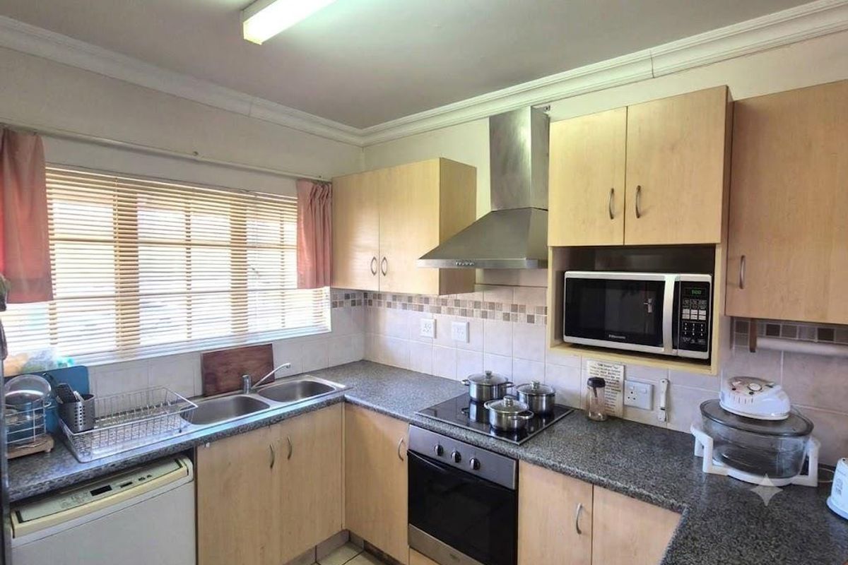 Functional kitchen featuring laminate cabinetry, granite countertops, stainless steel extractor fan, built-in oven, and a double bowl sink with tiled backsplash.