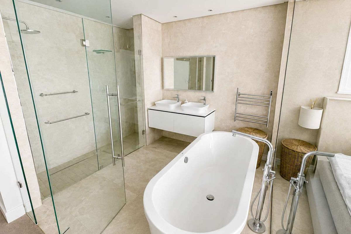 Modern penthouse bathroom featuring a sleek freestanding bathtub, glass-enclosed walk-in shower, and a contemporary double vanity with high-end stone finishes.