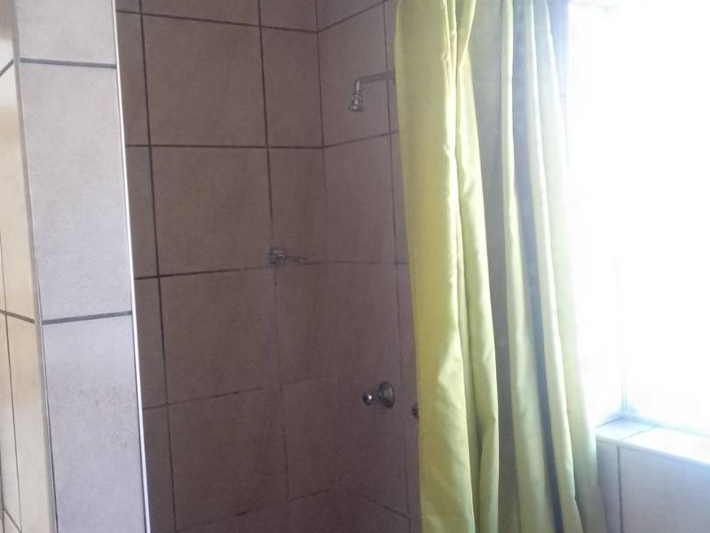 A functional bathroom shower area featuring tiled walls and flooring, requiring minor maintenance and cosmetic updates to improve its overall appeal.