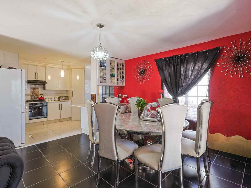 Open-plan kitchen and dining area featuring tiled flooring, built-in cabinetry, and integrated kitchen appliances, offering a functional layout for daily living.