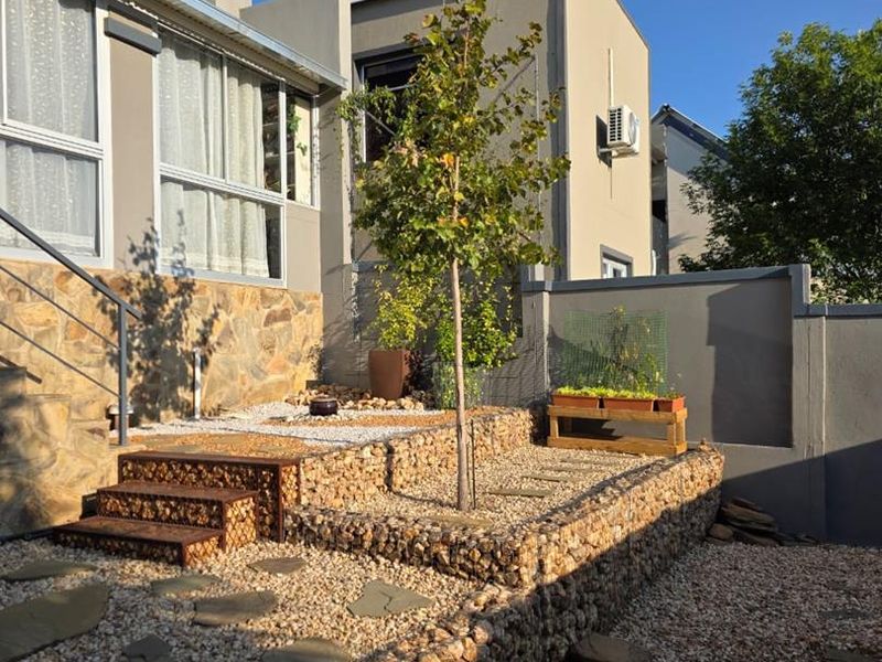 A well-maintained rear garden featuring tiered gabion retaining walls, stone cladding, and gravel landscaping, providing a structured and modern outdoor living space.