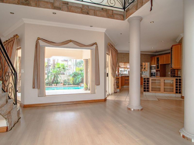 Spacious open-plan living area featuring a stone staircase, structural columns, and a view through to the pool area and kitchen.