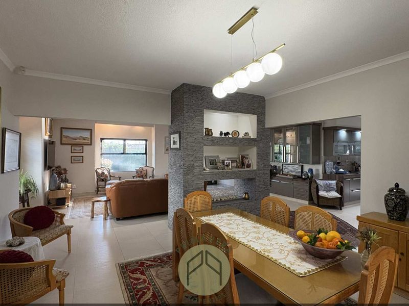 Spacious open-plan living and dining area featuring a central stone-clad feature wall with built-in shelving and modern pendant lighting.