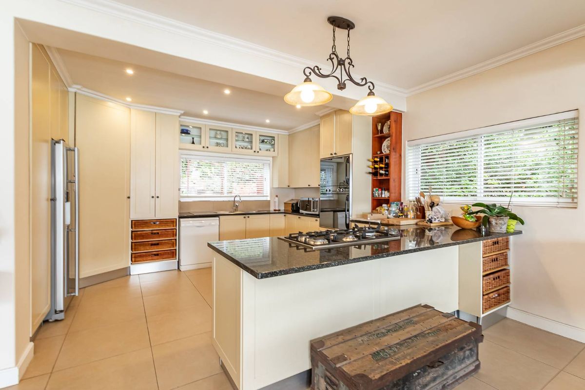 Spacious kitchen featuring granite countertops, a central island with a built-in gas hob, ample cabinetry, and integrated storage solutions.