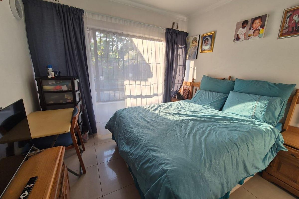 A functional bedroom featuring tiled flooring and a sliding glass door with security gate, providing access to the exterior.