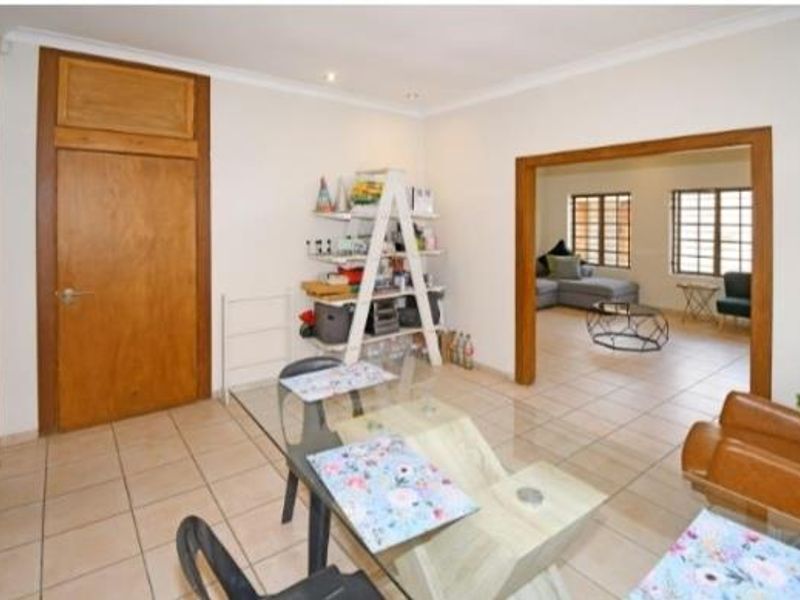 Open plan living and dining area featuring tiled flooring, wooden door frames, and coved cornicing, providing a versatile space for family living.