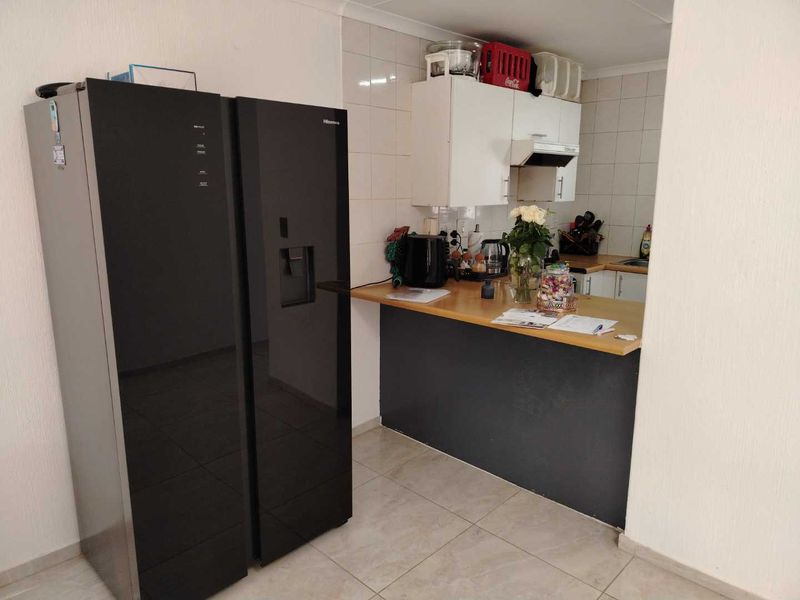 A functional kitchen area featuring built-in cabinetry, a tiled backsplash, and a breakfast counter, providing a practical space for meal preparation.