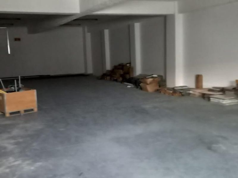 An open-plan industrial utility space featuring concrete flooring and exposed structural columns, suitable for storage or workshop use.