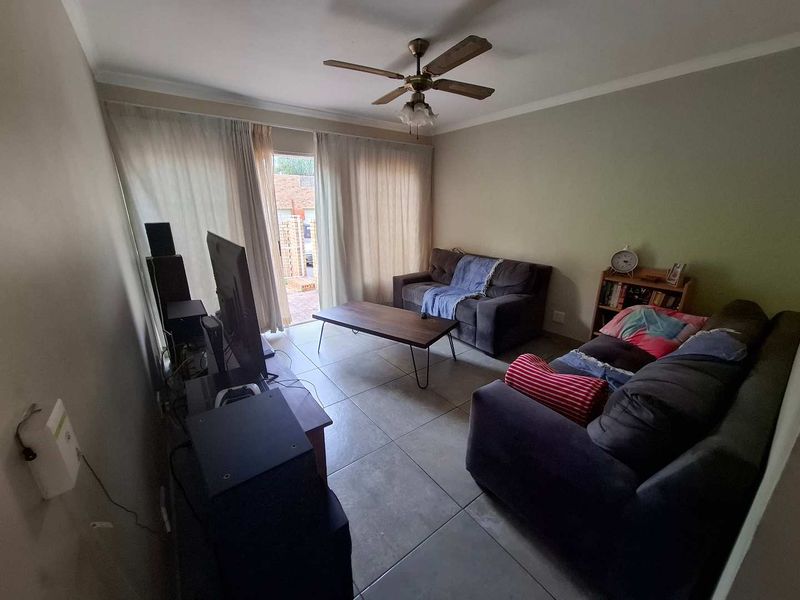 A living room featuring tiled flooring, a ceiling fan, and a sliding glass door providing access to the exterior.