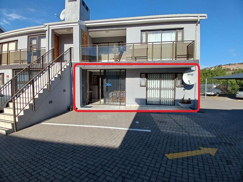Front elevation of a two-story cluster unit featuring a ground-floor patio, upper-level balcony with glass balustrades, and external staircase access.