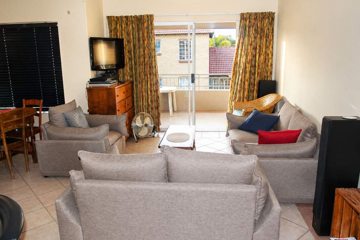 A living room featuring tiled flooring and sliding glass doors that open onto a private balcony, providing natural light and outdoor access.