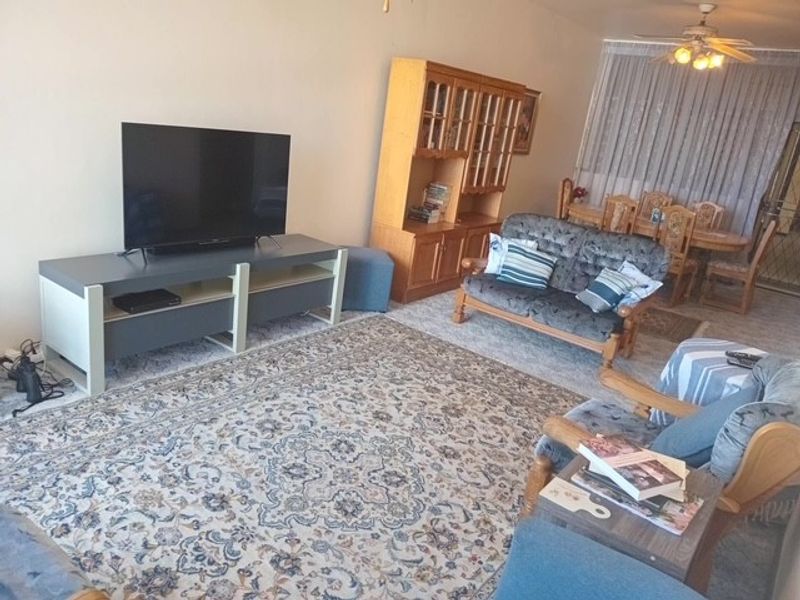 Open plan living and dining area featuring a ceiling fan and access to a balcony through sliding glass doors.