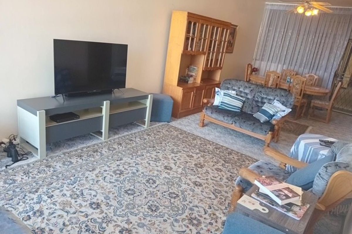 Open plan living and dining area featuring a ceiling fan and access to a balcony through sliding glass doors.