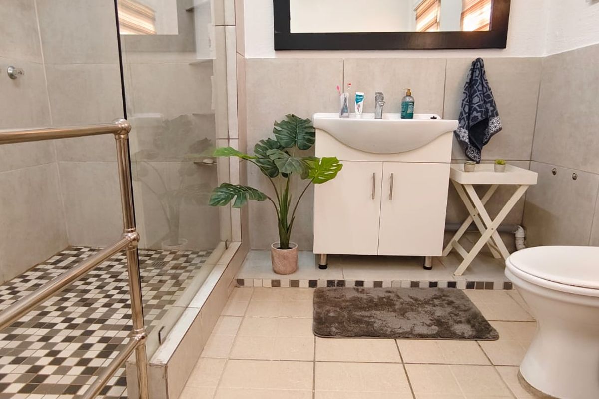A well-maintained bathroom featuring a walk-in shower with glass enclosure, a vanity cabinet with basin, and a standard toilet.
