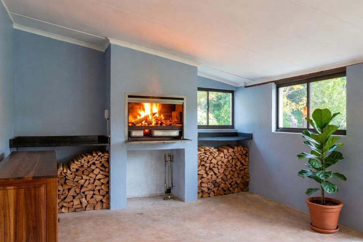 A cozy indoor braai area featuring a built-in fireplace, stone-topped side counters, and integrated firewood storage alcoves.