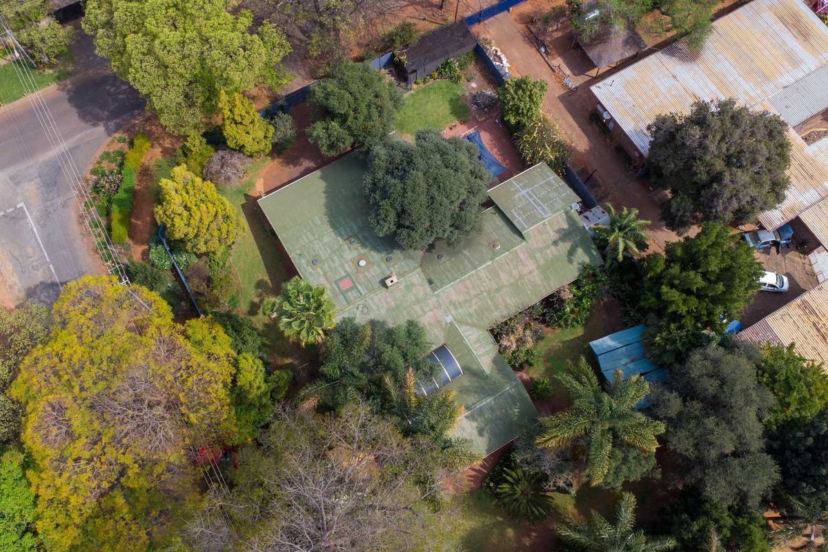 Aerial view of the property showcasing the roof structure, mature garden landscaping, and surrounding neighborhood context.