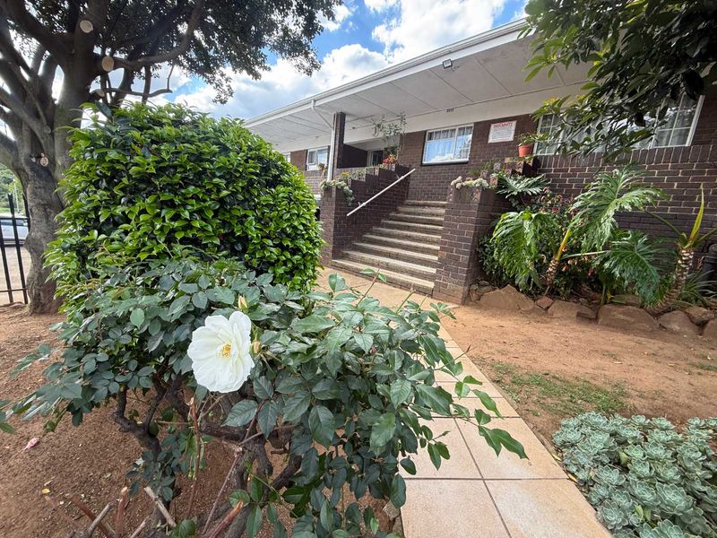 Front exterior view of the townhouse featuring a brick facade, concrete staircase with handrail, and a paved walkway leading to the entrance.
