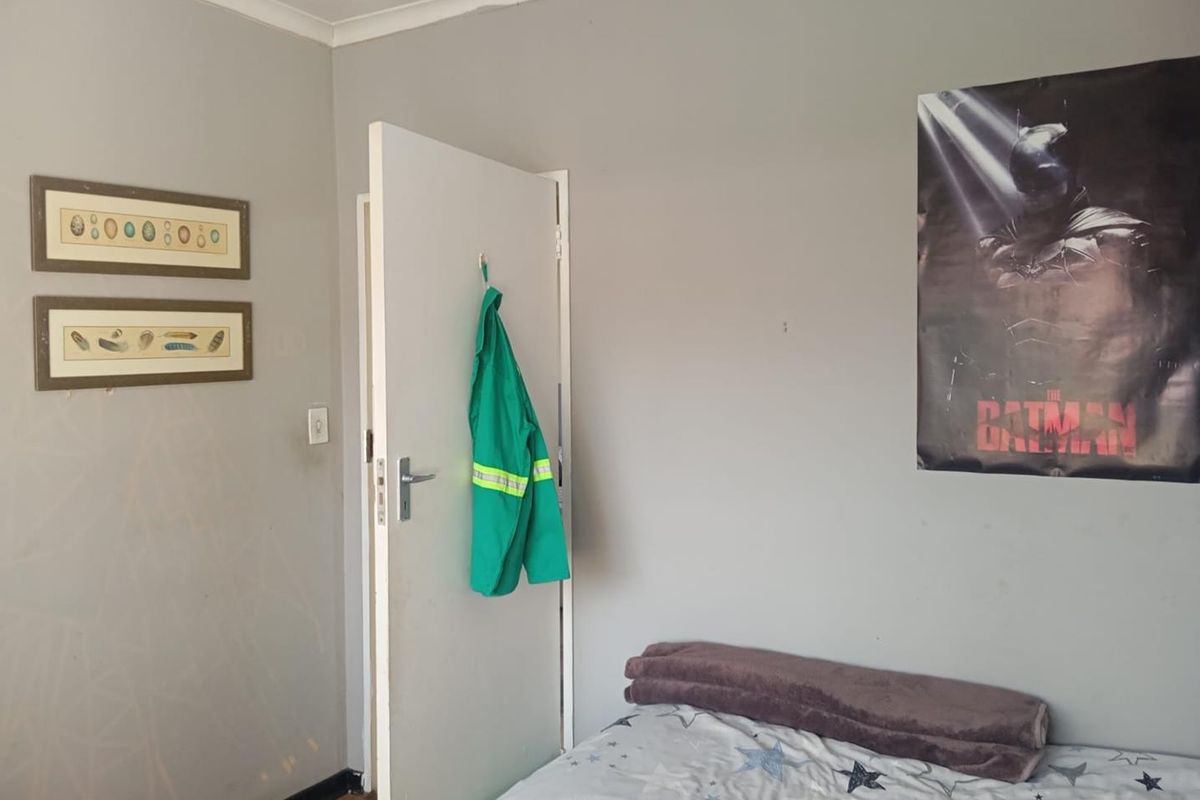 A bedroom featuring neutral grey walls, laminate flooring, and a standard interior door.