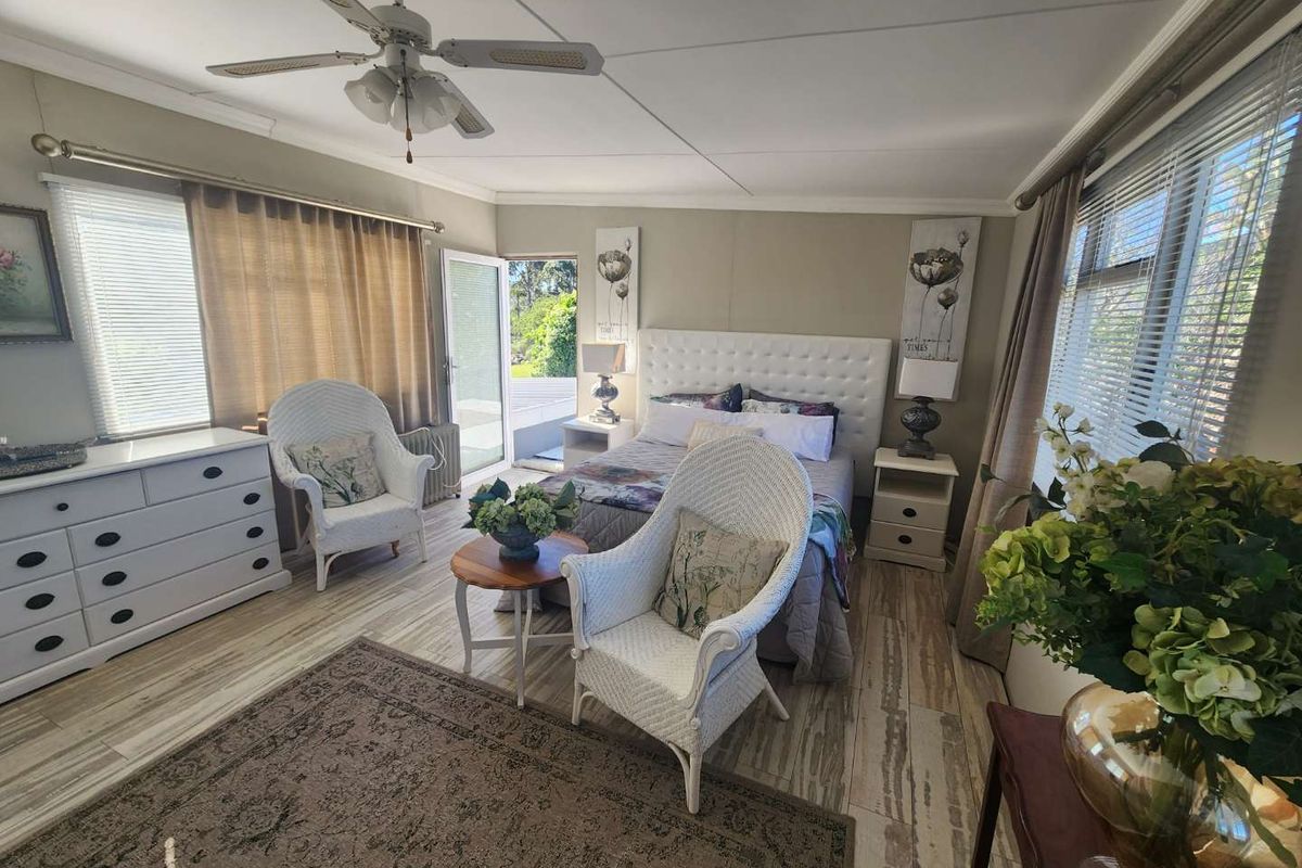 A bright and airy bedroom featuring tiled flooring, a ceiling fan, and direct access to an outdoor patio area through a glass door.