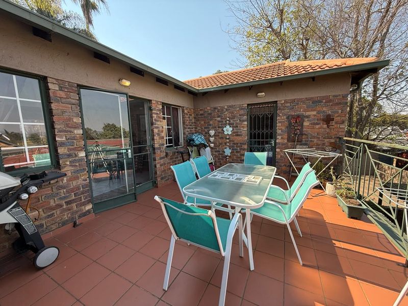 An outdoor patio area featuring face brick walls, tiled flooring, and direct access to the interior through a sliding glass door.
