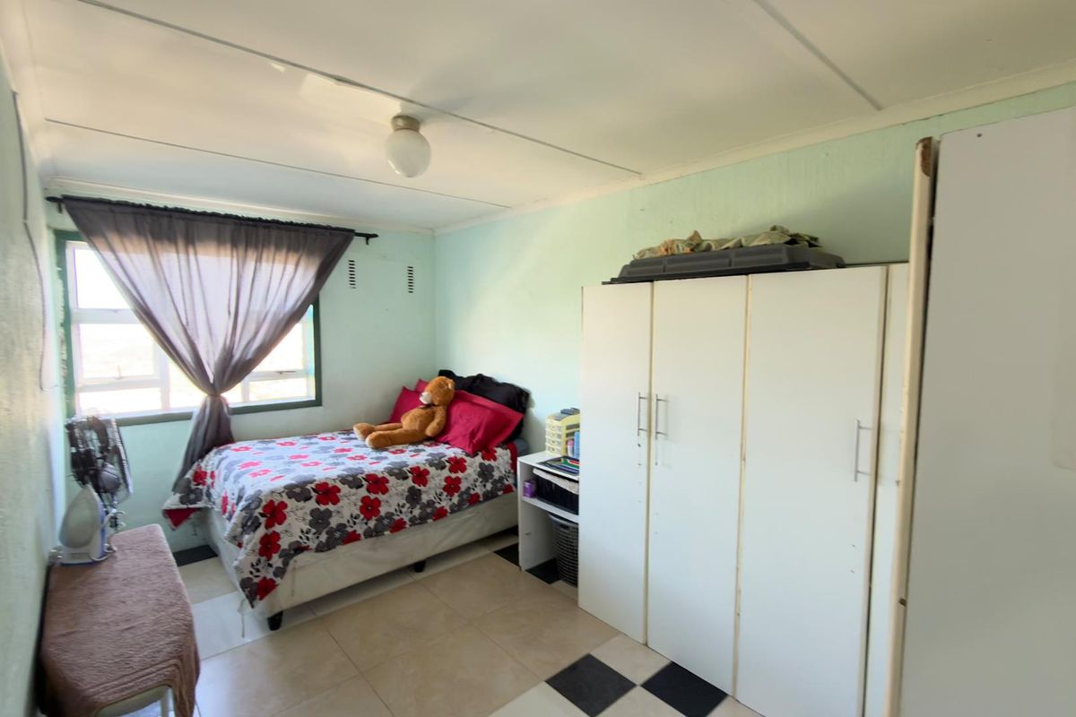 A functional bedroom featuring tiled flooring, a built-in wardrobe, and natural light from a window.