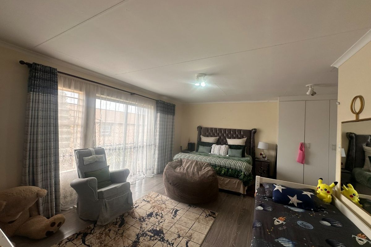 Spacious bedroom featuring laminate flooring, built-in cupboards, and a large sliding door providing ample natural light.