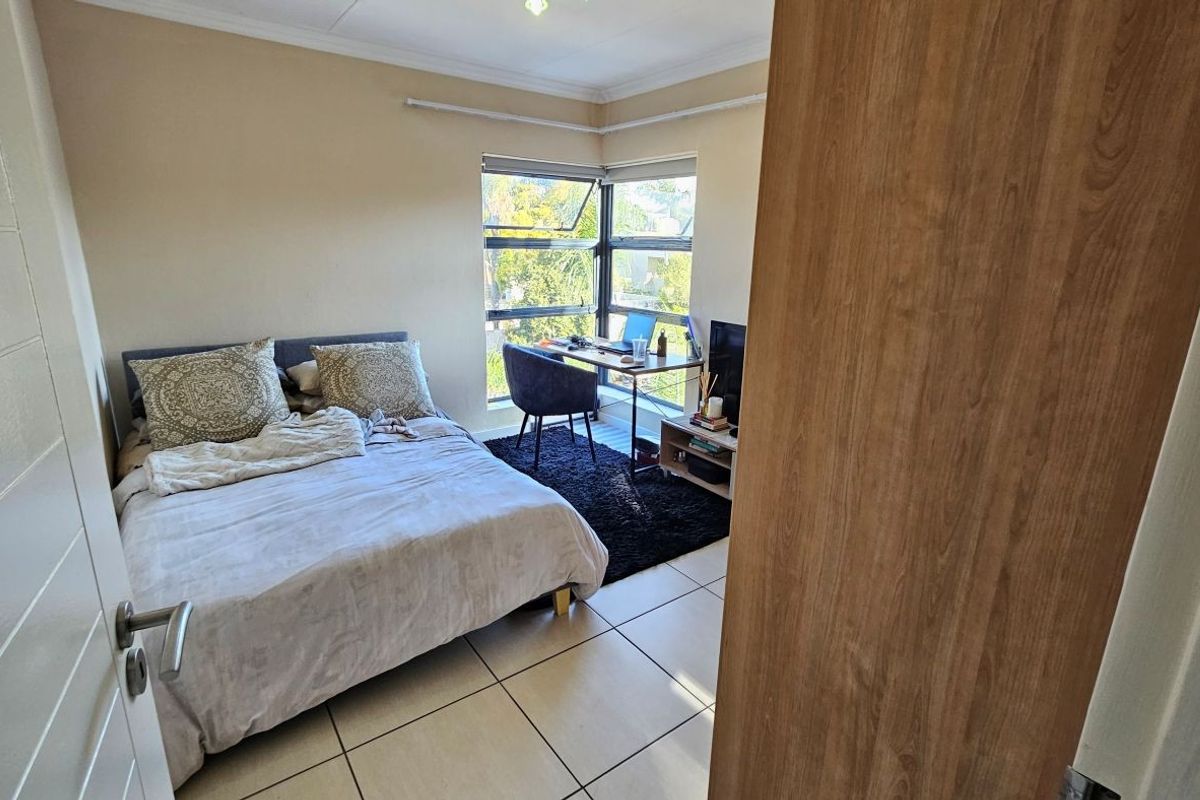 A bedroom featuring tiled flooring, a corner window providing natural light, and decorative cornice detailing.