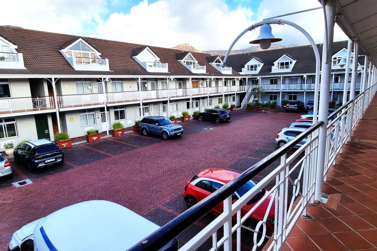 View of the office complex courtyard featuring paved parking area, covered walkways, and multi-level building facade with dormer windows.