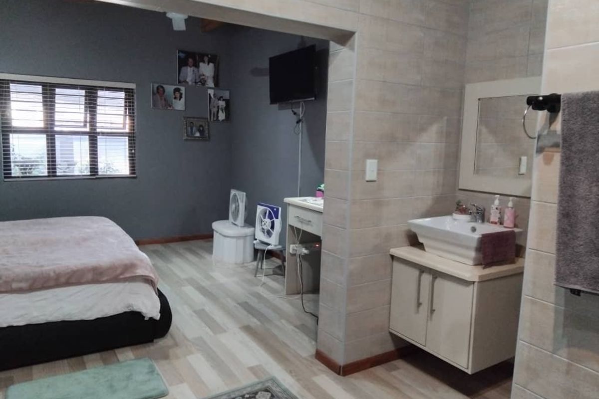 A bedroom featuring an open-plan layout with an integrated vanity area, tiled flooring, and neutral wall finishes.