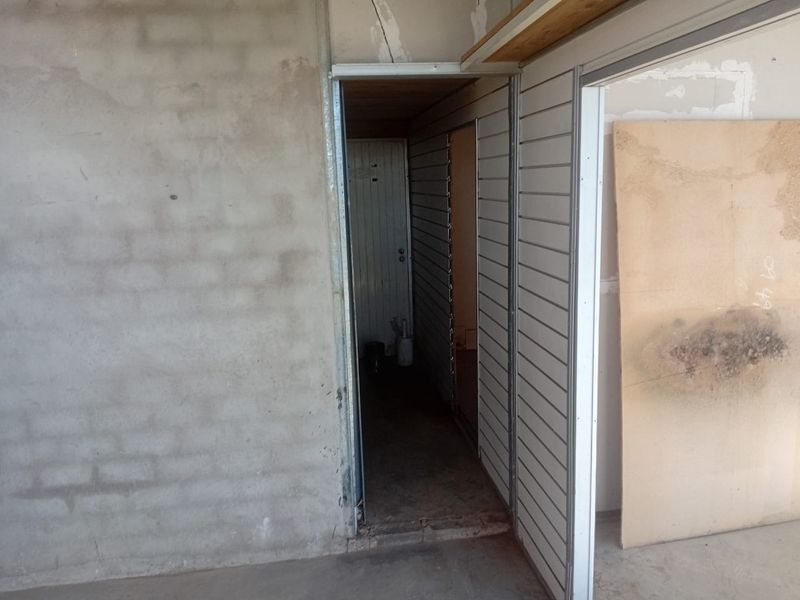 An unfinished utility or storage area featuring exposed concrete block walls and slatwall paneling, currently in a shell condition.