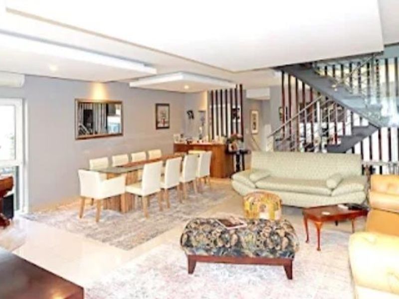 Spacious open-plan living and dining area featuring a modern staircase with glass balustrade, recessed ceiling lighting, and neutral tiled flooring.