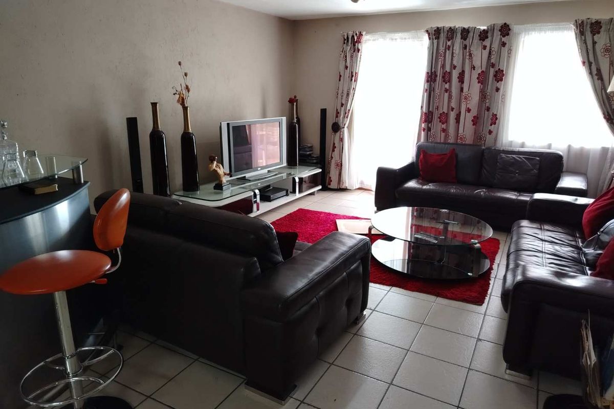 A spacious living room featuring tiled flooring and large windows with natural light, providing a comfortable area for relaxation and entertainment.