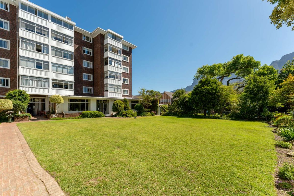 A view of the apartment building exterior featuring a well-maintained lawn and landscaped garden area.