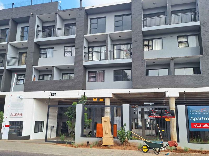 Modern multi-story apartment complex featuring secure gated access, electric fencing, and private balconies for each unit.